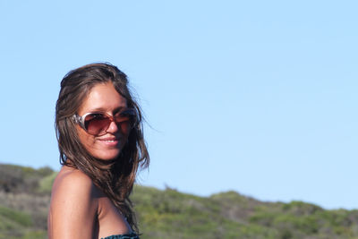 Portrait of smiling young woman against clear sky