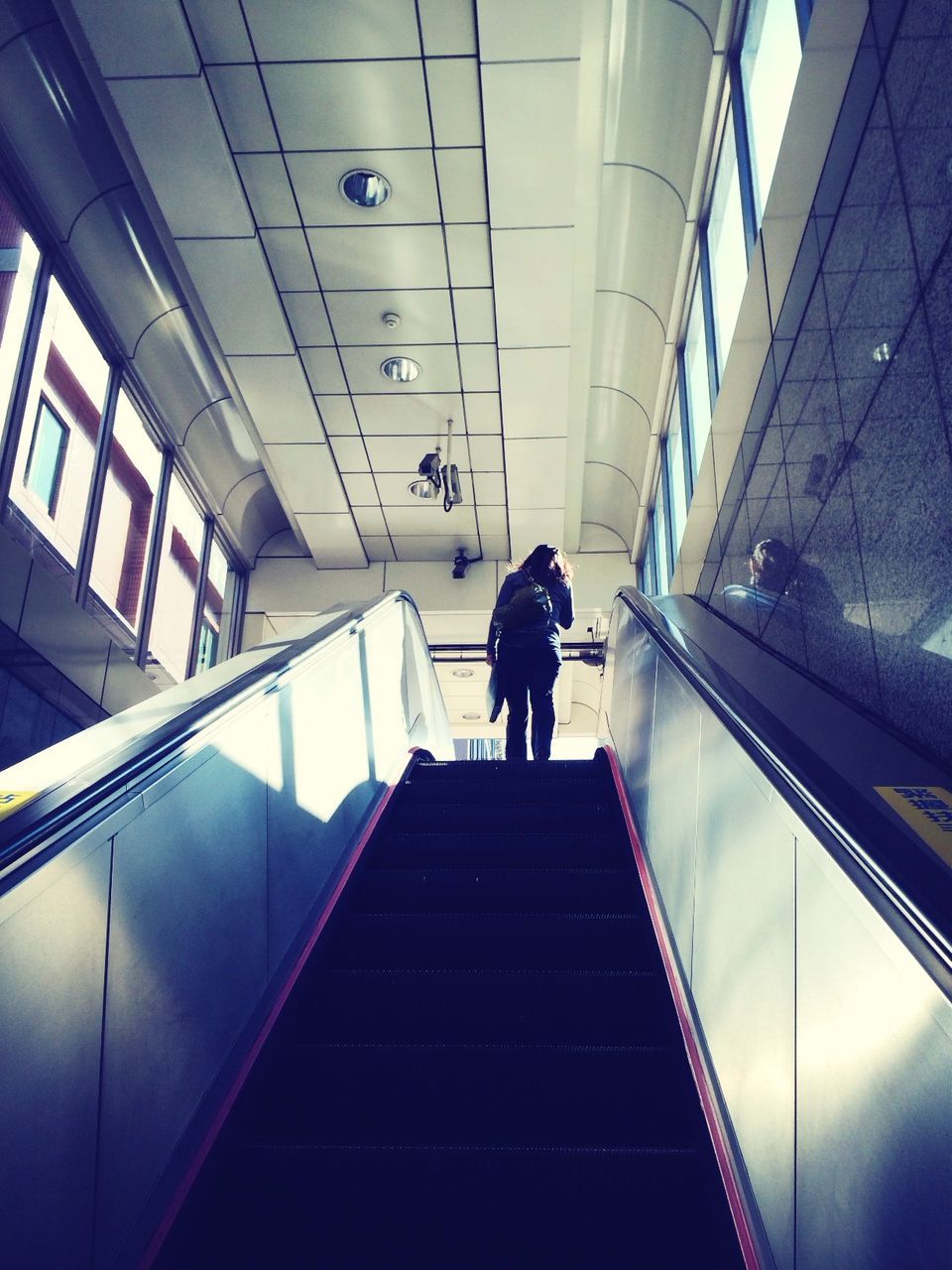 indoors, ceiling, architecture, built structure, modern, low angle view, illuminated, lighting equipment, glass - material, building, escalator, airport, window, the way forward, reflection, interior, travel, technology, diminishing perspective, skylight