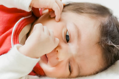 Close-up of cute baby girl relaxing on bed