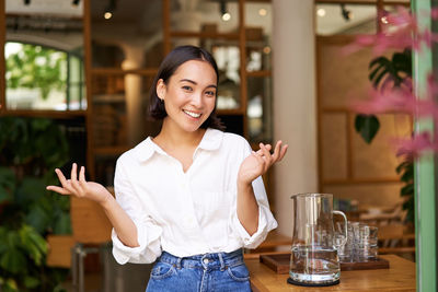 Portrait of young woman standing in cafe