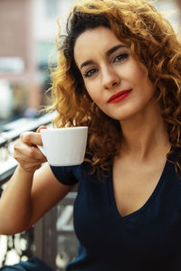 Young moroccan woman, with curly brown hair, sitting in an outdoor café in mainz, drinking coffee