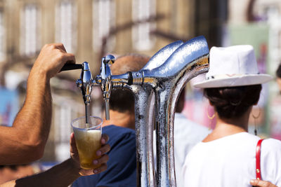 Barman serving draft beer pouring in street fest with people on background