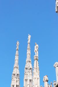 Low angle view of statues against blue sky