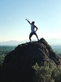 Full length of man standing on cliff against clear blue sky