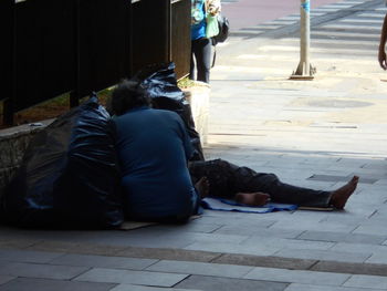 Rear view of people relaxing on sidewalk