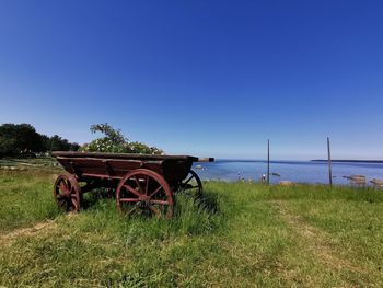 Tractor on field by sea against clear sky
