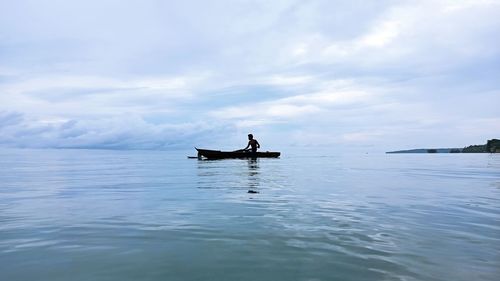 Man on boat in sea against sky