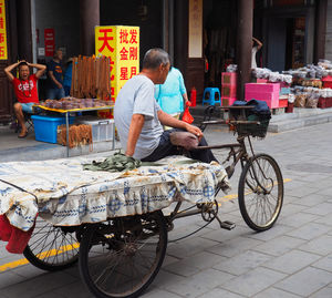 Full length rear view of man cycling on street in city