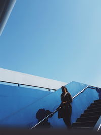 Man on staircase against clear blue sky