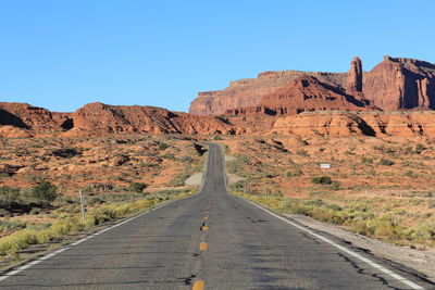 Empty road against clear blue sky