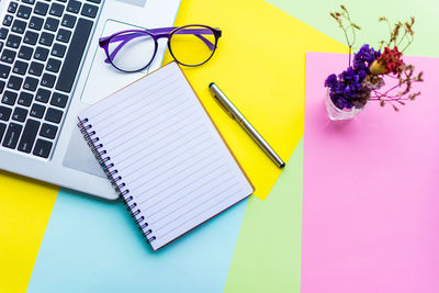 Spiral notebook with laptop on colorful papers