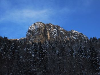 Low angle view of snow on rock against sky