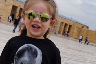 Close-up portrait of girl wearing sunglasses while standing against historic building