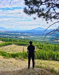 Rear view of man standing on mountain against sky