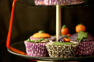 Close-up of halloween cupcakes on cakestand against black background