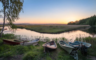 Boats moored by lake against clear sky during sunset