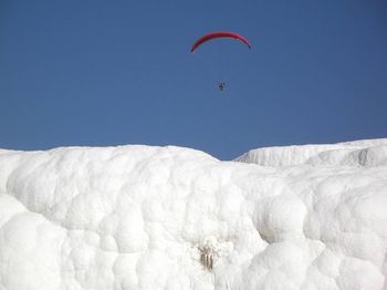 Person paragliding at over snow covered landscape