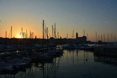 Sailboats moored at harbor during sunset