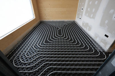 High angle of radiant heating systems with pipes installed on floor in contemporary wooden cottage