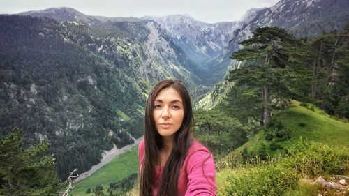 Portrait of young woman standing against mountains