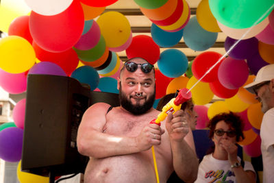 Full length of shirtless man holding balloons