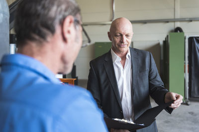 Two men with clipboard in factory