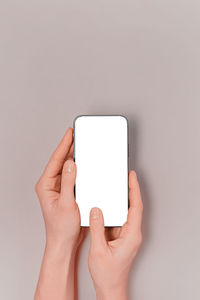 Cropped hands of woman using mobile phone against white background