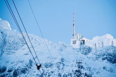 Snow covered land, weatherstation and mountains against clear blue sky