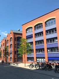 Bicycle by building against clear blue sky
