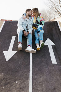 Young couple sitting between the signs on the floor of a skate park