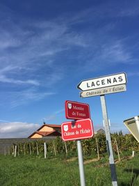 Road sign on field against sky