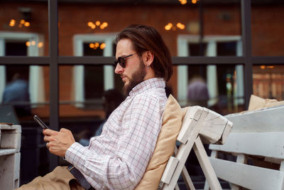 Side view of man wearing sunglasses while sitting at cafe