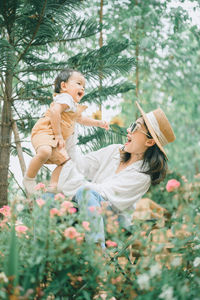 Cheerful mother holding son mid air while standing at park