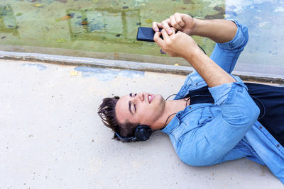 Man listening music while using mobile phone in city