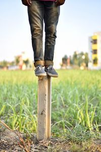 Low section of man standing on bollard against field