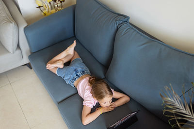 High angle view of woman using digital tablet while sitting on sofa at home