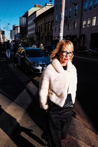 Young woman standing by car in city