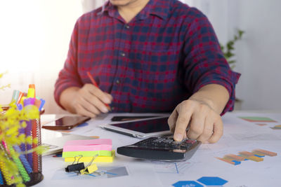 Midsection of woman holding paper while sitting on table