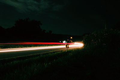 Light trails on road against sky at night