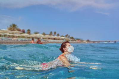 Young woman wearing mask swimming in sea