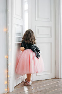 Rear view of girl standing against door