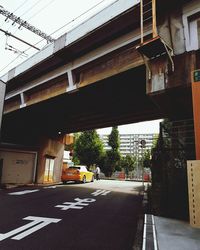 Road by bridge in city against sky