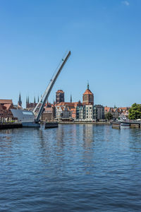 River by buildings against clear blue sky