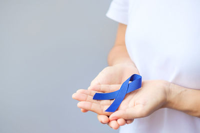 Midsection of doctor holding pills against white background