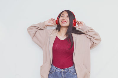 Portrait of smiling young woman standing against white background