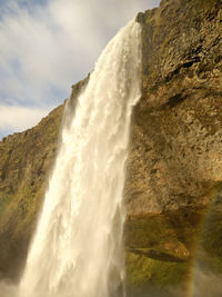 Low angle view of waterfall on mountain against sky