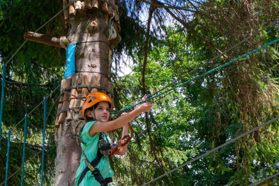 Adventure climbing high wire park - people on course in mountain helmet and safety equipment