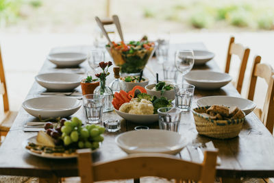 Dining table with bowls and plates arranged at patio in backyard