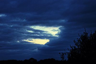 Low angle view of silhouette trees against dramatic sky