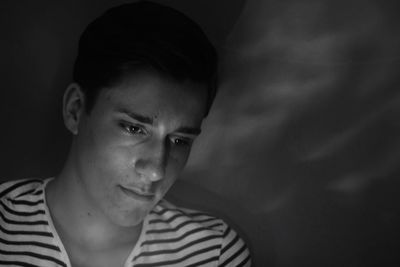 Close-up of thoughtful teenage boy by wall in darkroom
